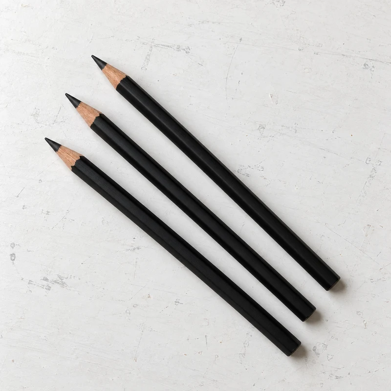 Charcoal pencils on a lightly marked white studio table