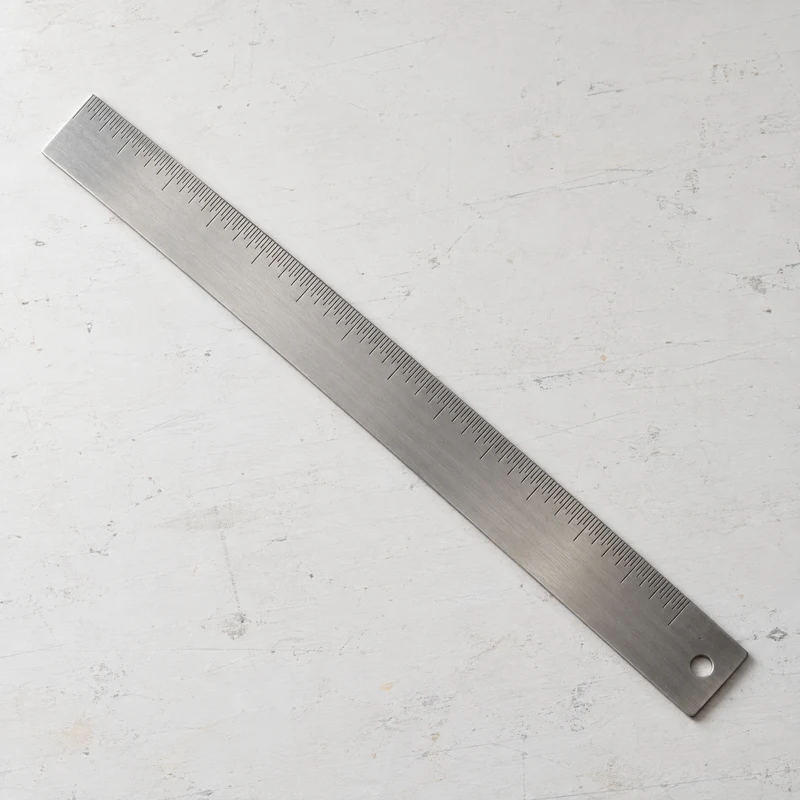 Metal ruler on a lightly marked white studio table