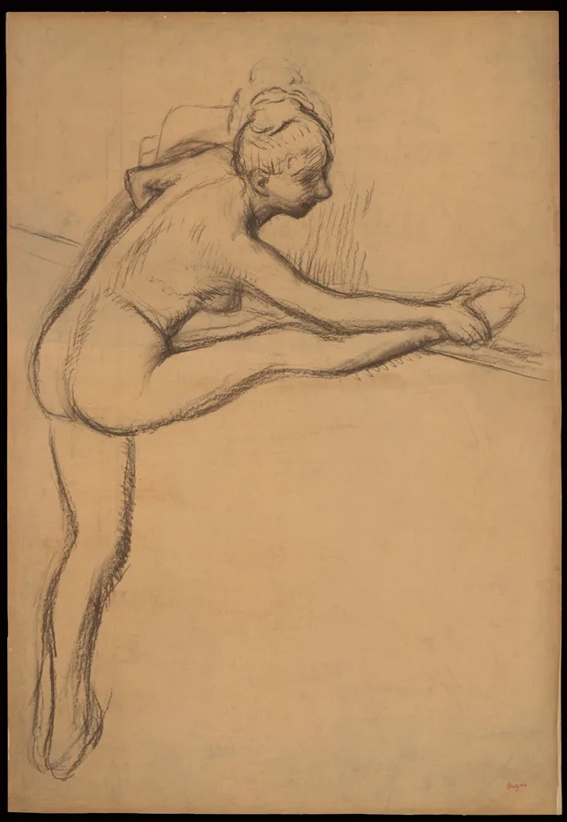 A female dancer stretching toward her foot at a barre.